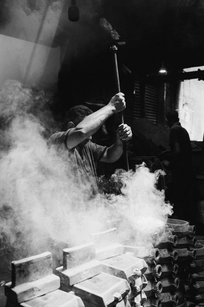 A blacksmith in Alexandria, Egypt works amidst steam, creating a dramatic and moody scene.