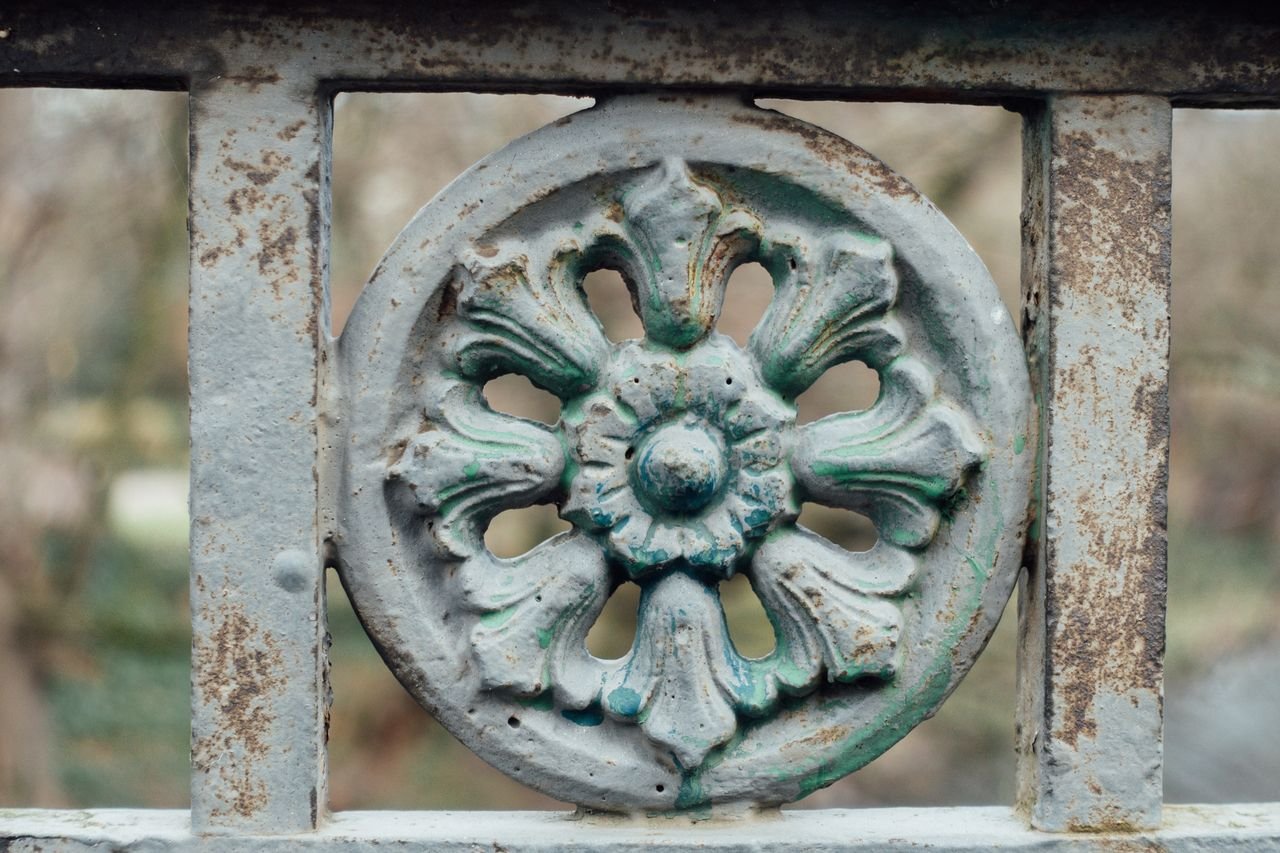 Close-up of an ornate rusted metal fence with floral design, showcasing vintage craftsmanship.